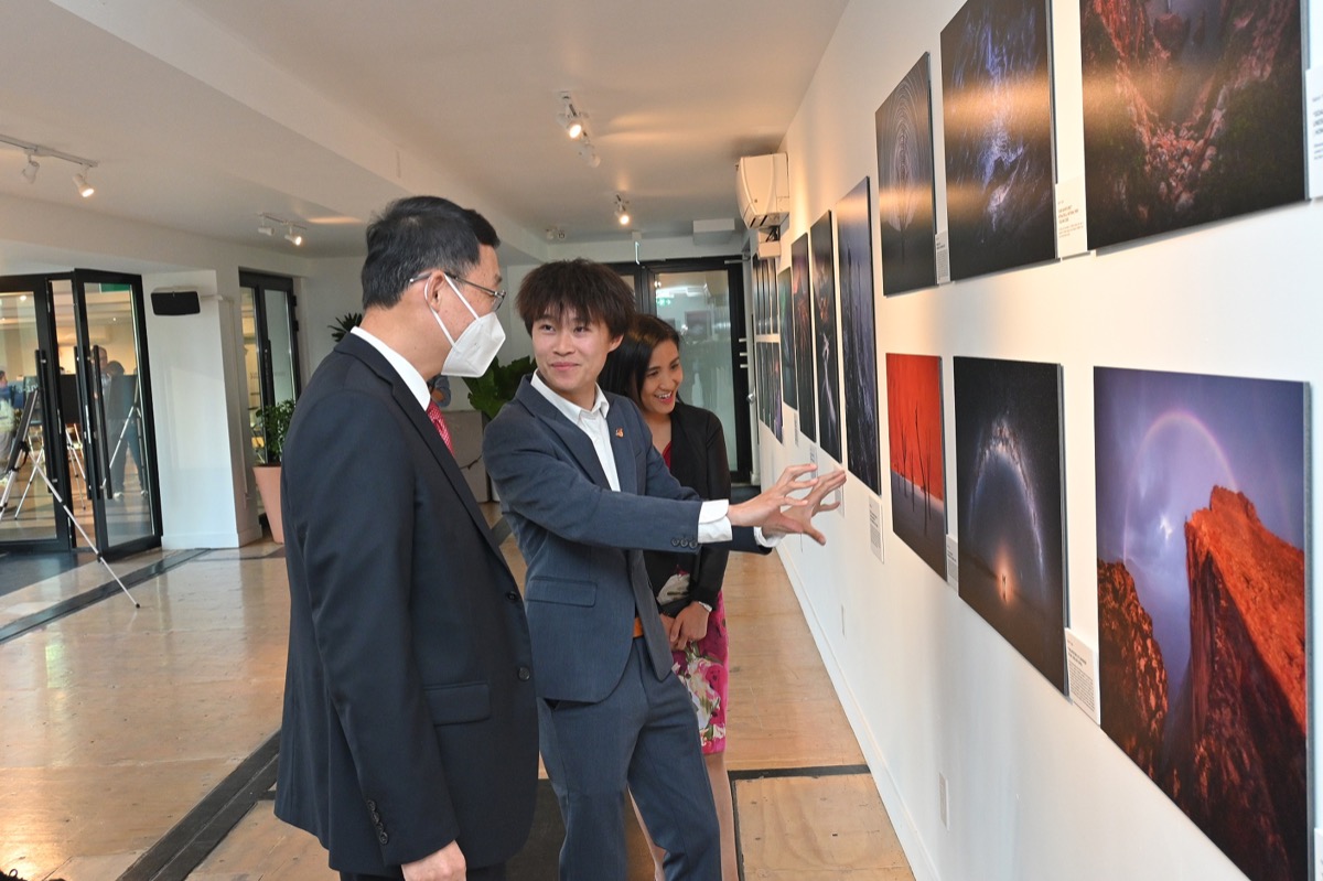 香港駐多倫多經濟貿易辦事處處長巫菀菁（右一）於十月四日參觀「大地之旅」攝影展時，與中國駐多倫多總領事韓濤（左一）聆聽香港攝影師袁斯樂（中）的介紹。